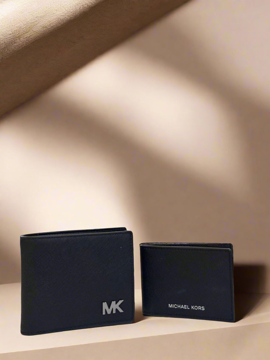 Two black Michael Kors wallets on a table with a blurred indoor background