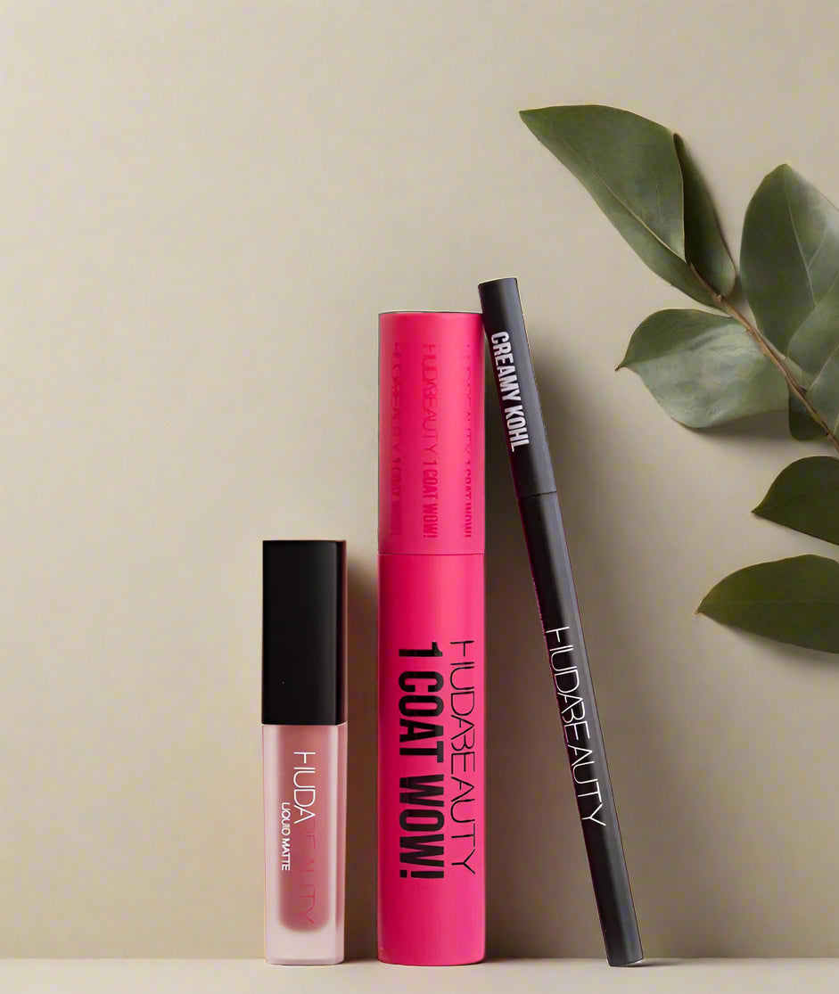 Huda Beauty makeup products on a light pink background