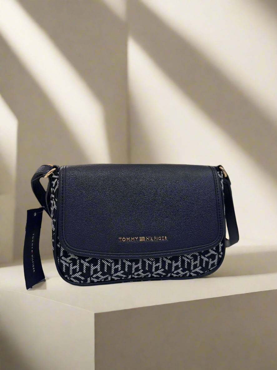 Black handbag with Tommy Hilfiger logo on a marble surface with a blurred indoor background